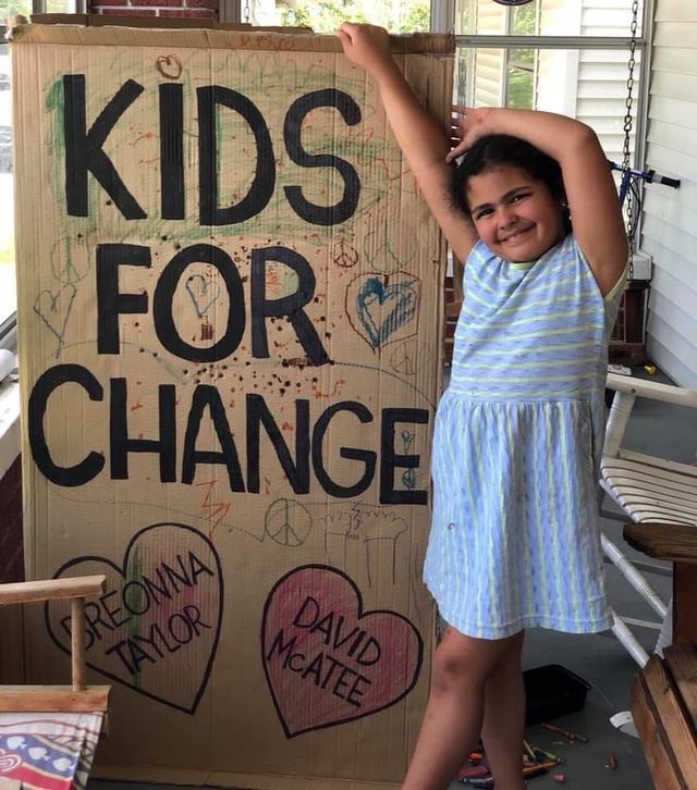Figure 2: A child poses next to her poster stating 'Kids for Change' for a Louisville protest against police shootings of Black people in June 2020. Breonna Taylor and David McAtee's names are written in hearts. Figure 2